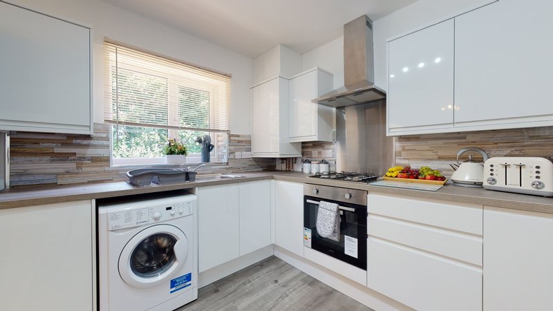 Modern kitchen with white cabinetry, wood countertops, stainless steel appliances, and washing machine