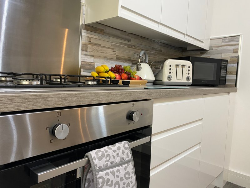 Modern kitchen with stainless steel appliances, white cabinetry, and countertop with fruit bowl and toaster