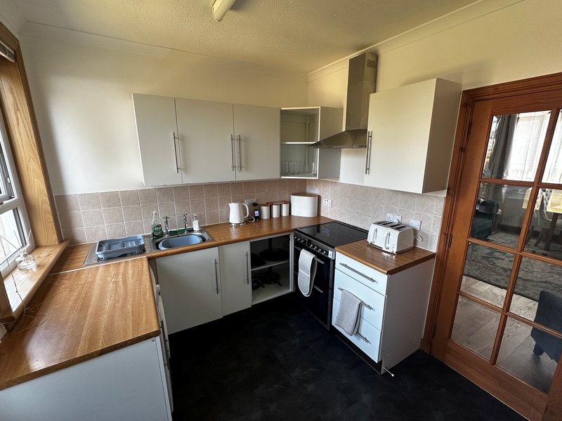 Modern kitchen with white cabinets, appliances (oven, washing machine and fridge/freezer) and wooden worktops. Microwave/toaster/kettle and crockery/cutlery/glassware provided.