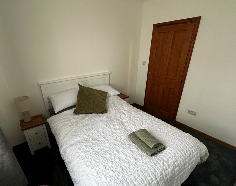 Bedroom with double bed, bedside tables, hanging space and front facing window.