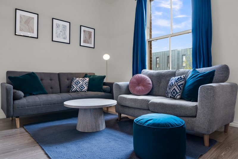 Modern living room with grey sofas, blue cushions, round coffee table and large window
