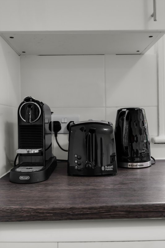 Kitchen counter with black coffee maker, toaster, and kettle appliances