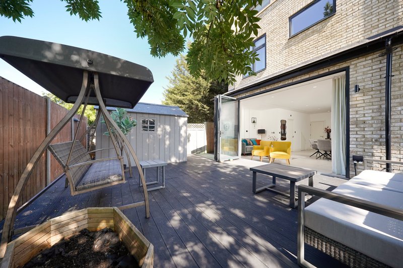 Modern brick house with open patio area, seating, and large sliding glass doors leading to interior living space