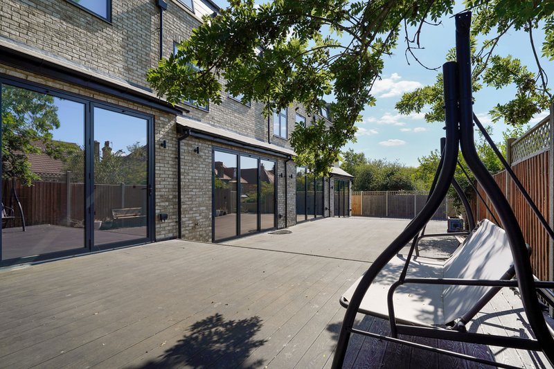 Modern brick extension with patio, large windows, garden furniture and climbing ivy