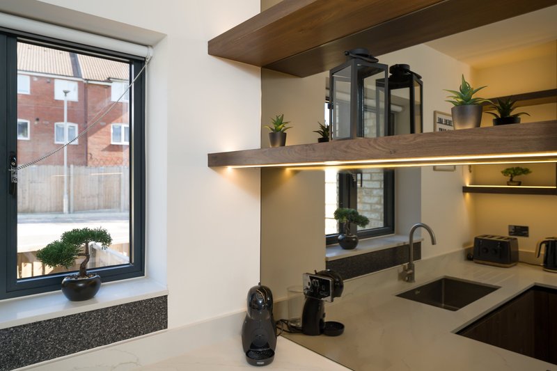 Modern kitchen with floating shelves, sink, window view and potted plants