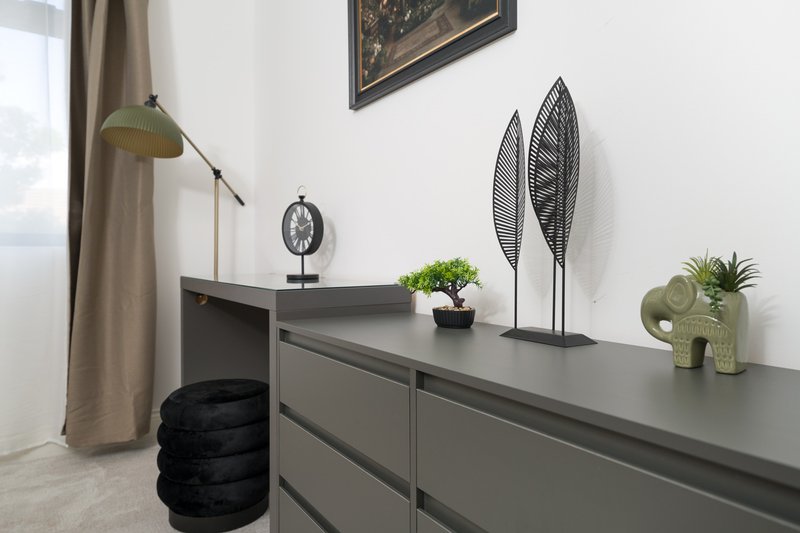 Modern bedroom workspace with grey desk, decorative plants, wall art and floor lamp