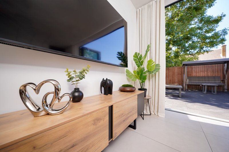 Modern living room with wooden sideboard, decorative objects, potted plants and view to garden