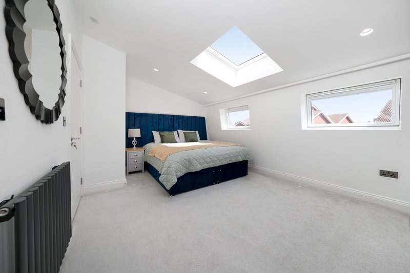 Bright attic bedroom with skylight, navy bed frame, and modern furnishings