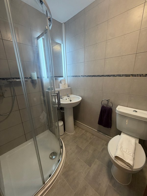 Modern bathroom with shower cubicle, pedestal sink, toilet and tiled walls