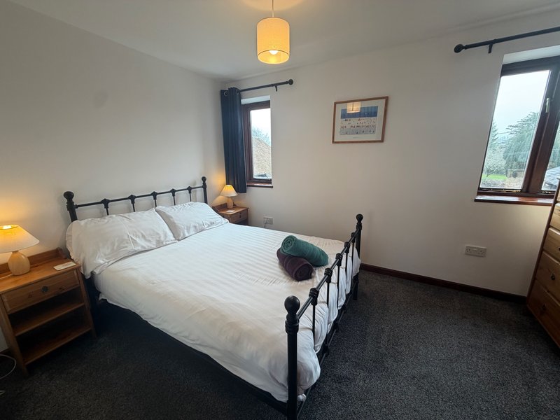 Bright bedroom with double bed, metal frame, white bedding, wooden nightstands, pendant light fixture
