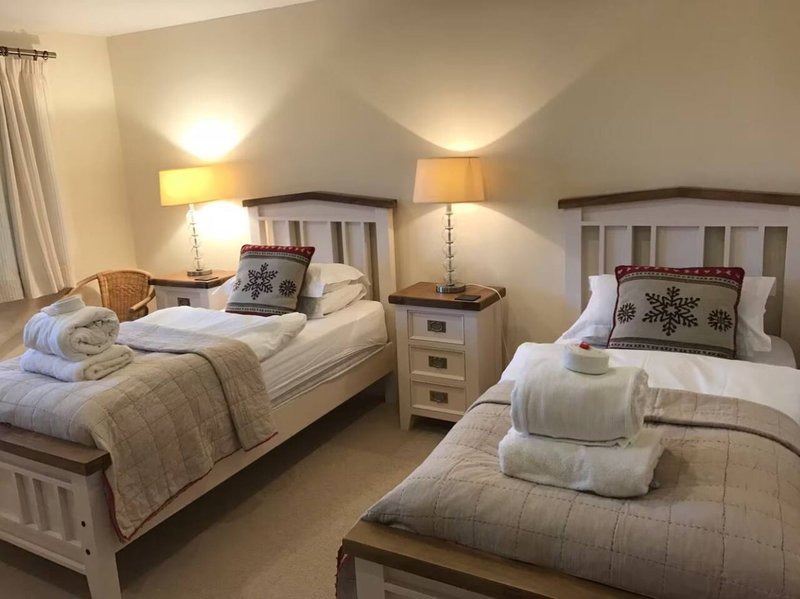 Twin bedroom with two single beds, bedside lamps, cushions and rolled towels
