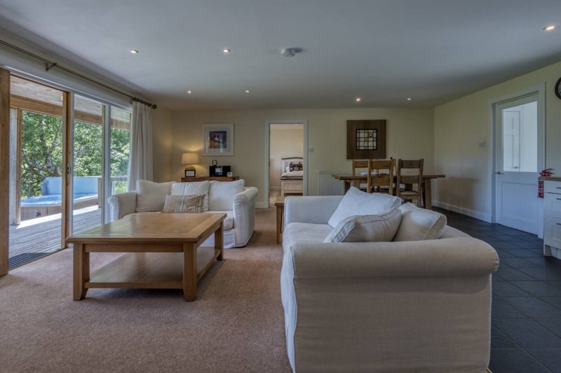 Spacious open-plan living area with cream sofas, wooden coffee table, and patio doors to garden