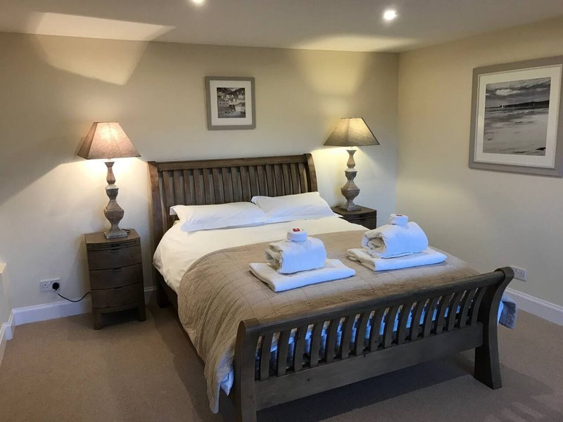 Spacious bedroom with double bed, two bedside lamps, framed artwork and blue towels