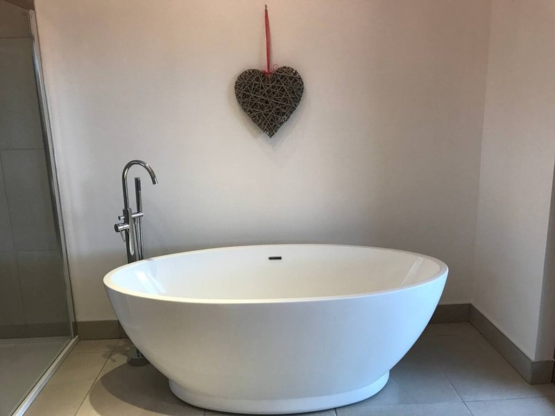 Modern freestanding white bath with floor-mounted faucet and heart decoration