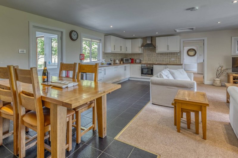 Open-plan kitchen and dining area with wooden table, cream cabinetry, and French doors to garden