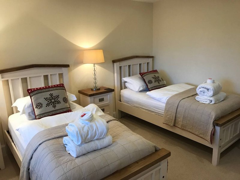 Twin bedroom with two single beds, bedside lamp, and rolled towels on each bed