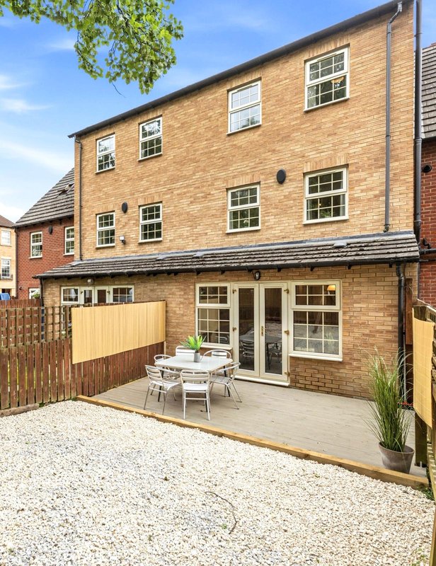 Brick townhouse with patio, garden furniture, and wooden fence
