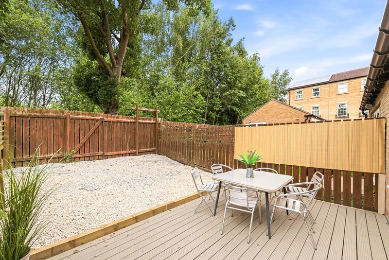 Spacious garden deck with dining table, chairs, gravel area and wooden fencing