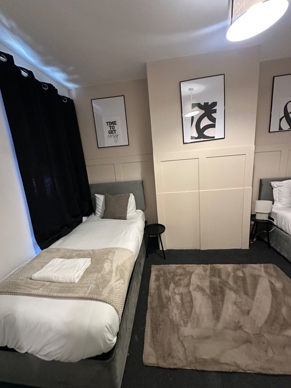 Shared bedroom with two single beds, white bedding, framed wall art, and pendant ceiling light