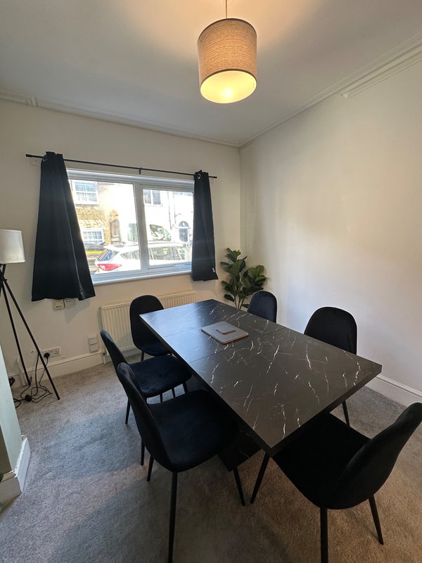 Dining room with dark marble table, black chairs, pendant lamp, and window with black curtains