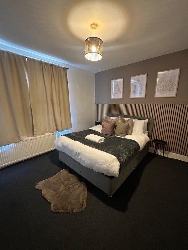 Modern bedroom with double bed, pendant light, radiator and framed wall art