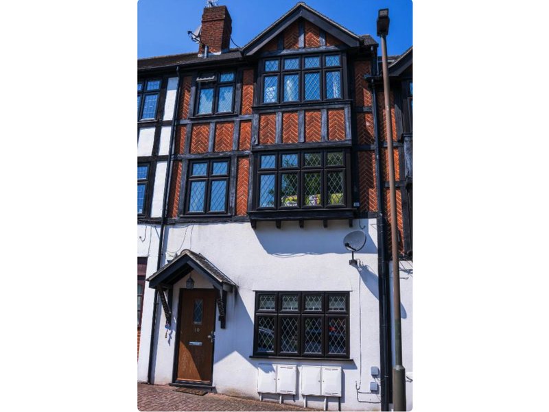 Traditional Tudor-style house with brick and white exterior, leaded windows and wooden door