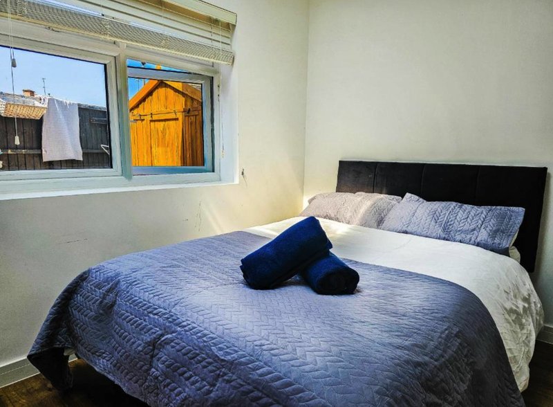 Bedroom with double bed, blue bedding, black pillows, and window with exterior view