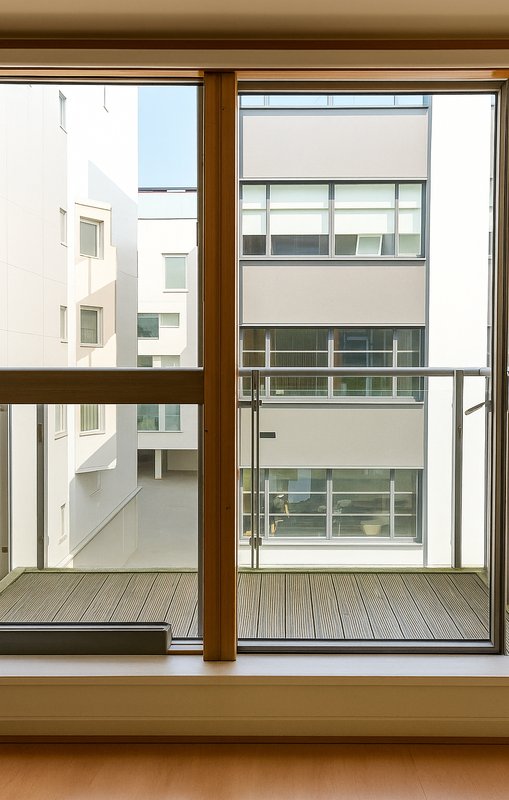 Interior view through large wooden-framed windows overlooking apartment building courtyard