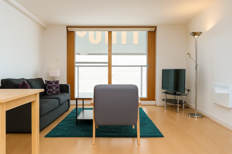 Modern living room with sofa, armchair, wooden table, teal rug and glass doors