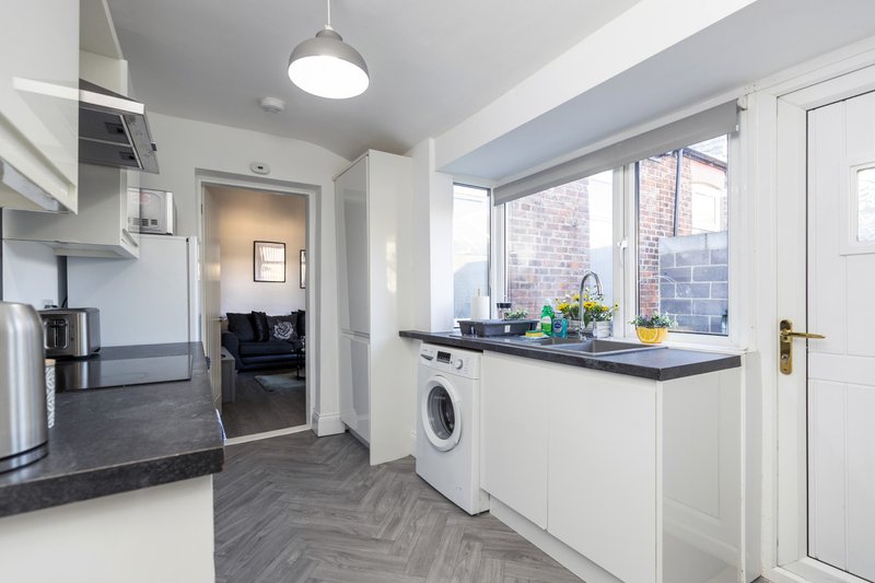 Modern kitchen with washing machine, counter space, pendant lighting and large windows