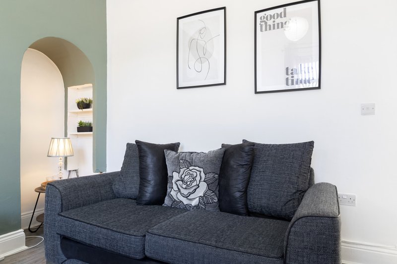 Modern living room with dark grey sofa, decorative cushions, and framed wall art