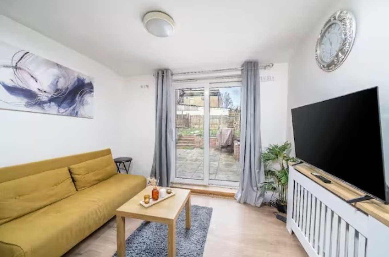 Bright living room with yellow sofa, TV, wooden coffee table and garden view