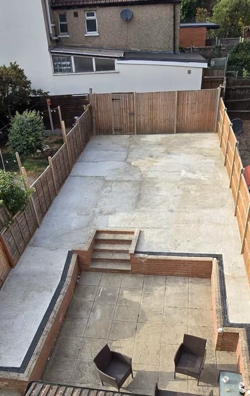 Paved garden courtyard with wooden fencing, steps, and brick planter boxes