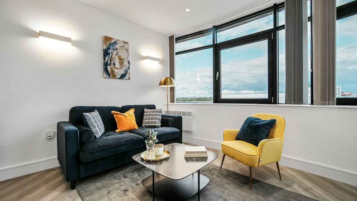 Modern living room with blue sofa, yellow armchair, and panoramic window views of landscape