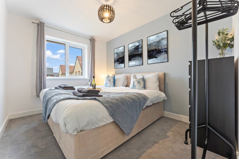 Modern bedroom with double bed, grey bedding, window with city view, and pendant light