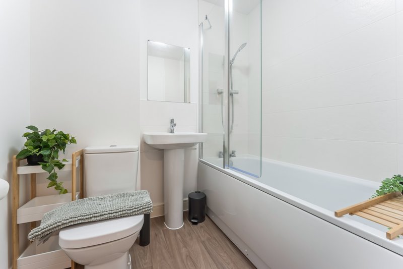 Modern bathroom with toilet, pedestal sink, bathtub, shower enclosure and potted plants