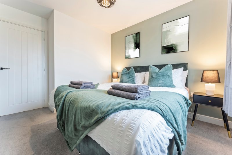 Modern bedroom with double bed, teal bedding, wall art, and wooden nightstands