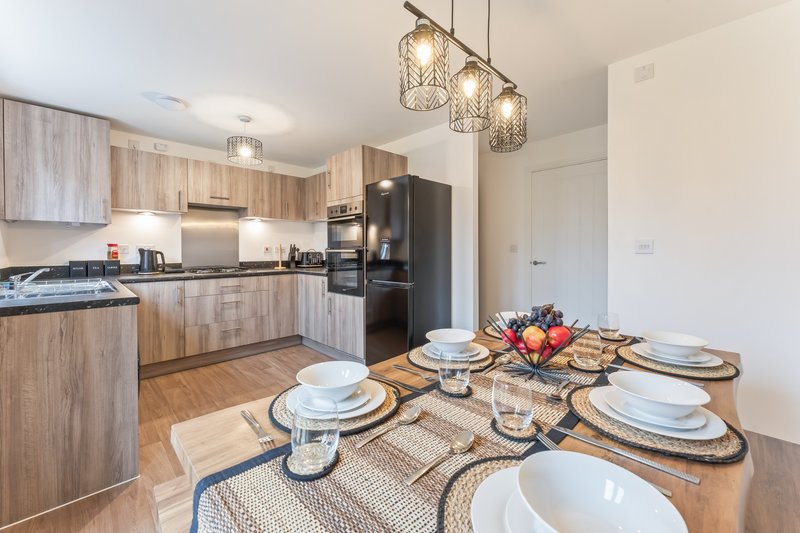 Open-plan kitchen and dining area with wooden cabinetry, stainless steel appliances, and dining table set for four