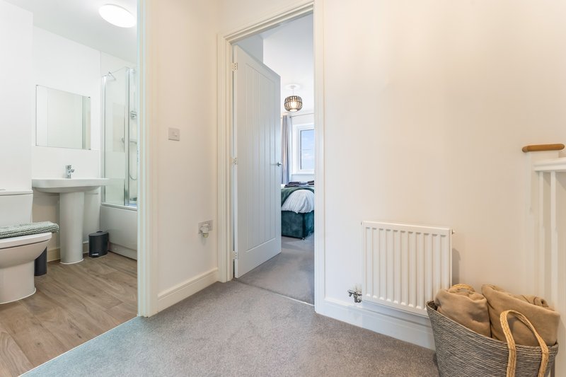 Hallway with bathroom door, bedroom entrance, radiator and woven storage basket