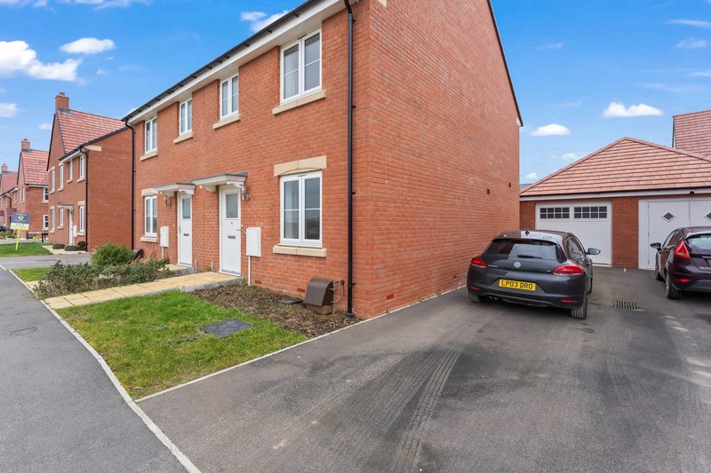 Modern brick detached house with driveway, parked car, and garage on suburban street