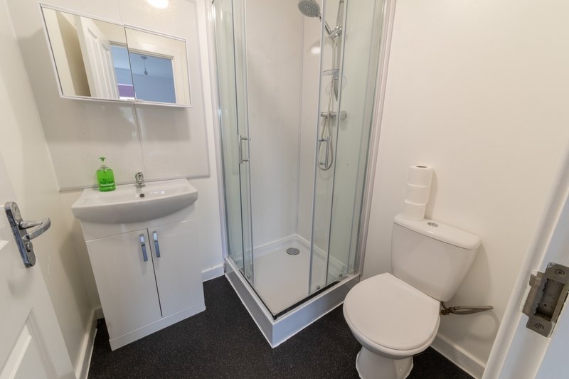 Clean modern bathroom with white fixtures, shower enclosure, sink and toilet