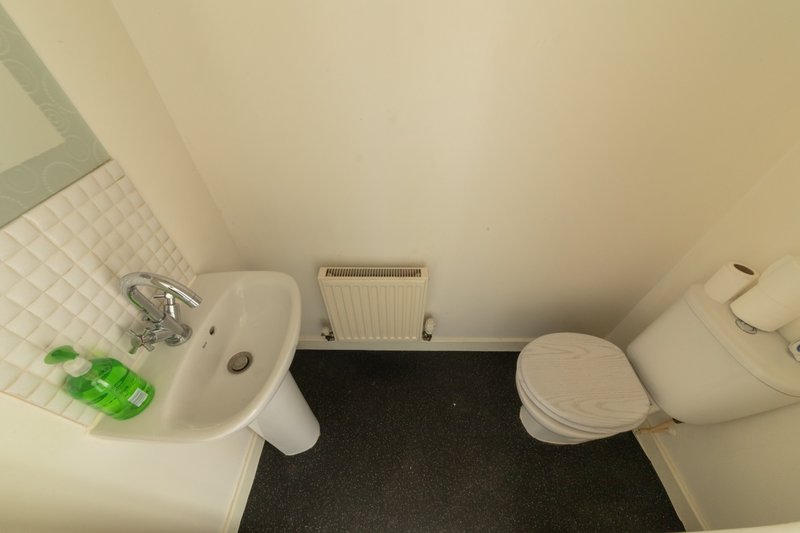 Small bathroom with sink, toilet, radiator and black floor mat