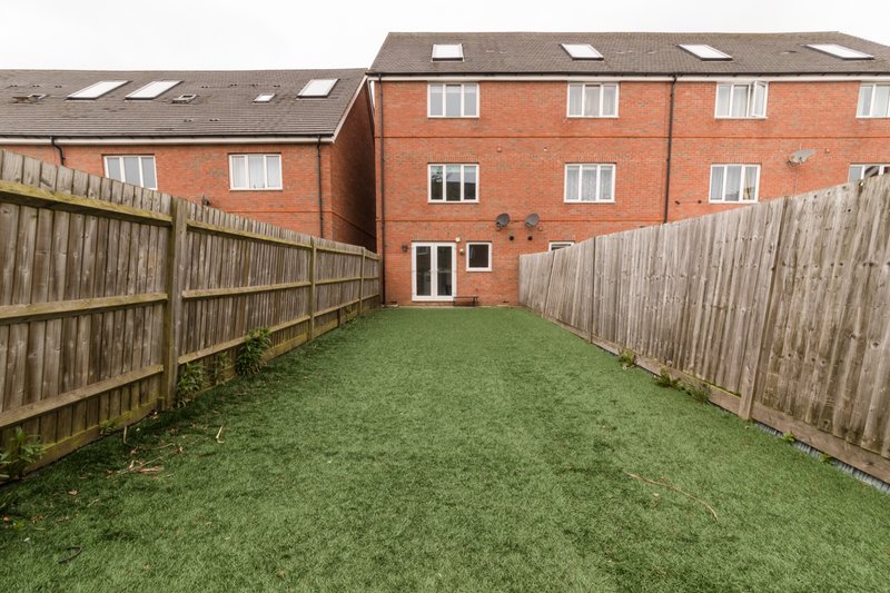 Brick townhouse with rear garden, wooden fence, and green lawn