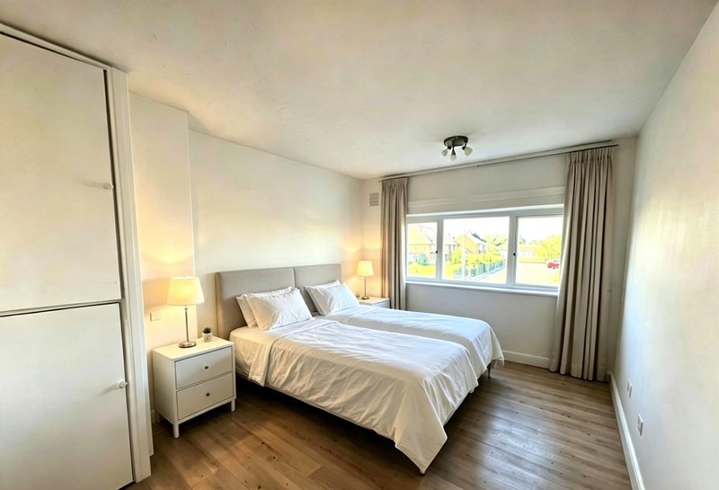 Bright bedroom with double bed, wooden floor, bedside lamps and large window with curtains