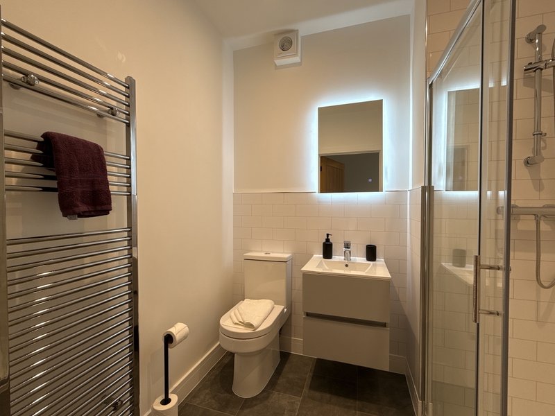 Modern bathroom with toilet, sink vanity, heated towel rail and walk-in shower