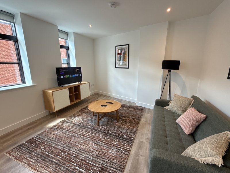 Modern living room with grey sofa, wooden coffee table, storage unit and TV stand