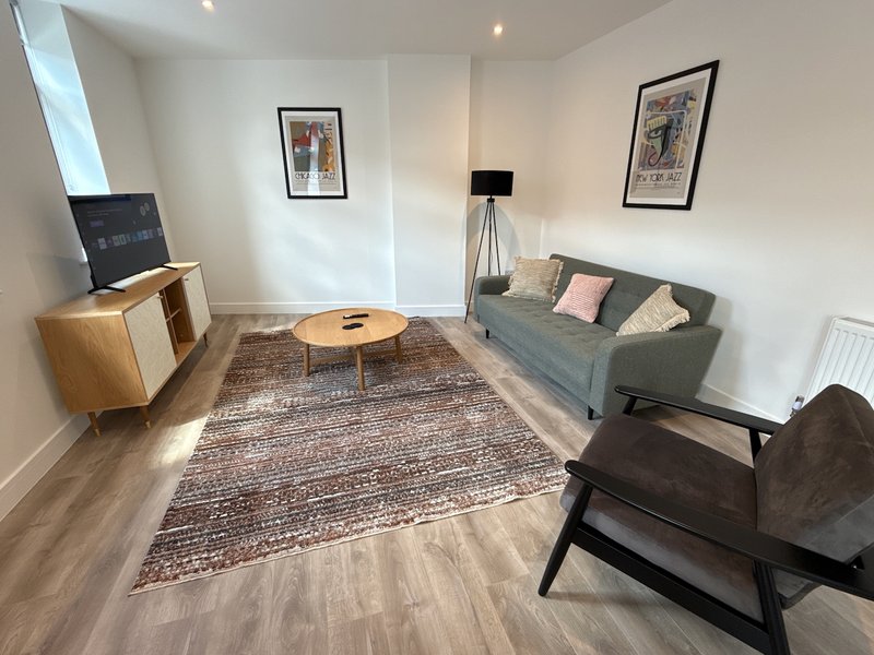 Modern living room with grey sofa, wooden furniture, patterned rug and framed wall art