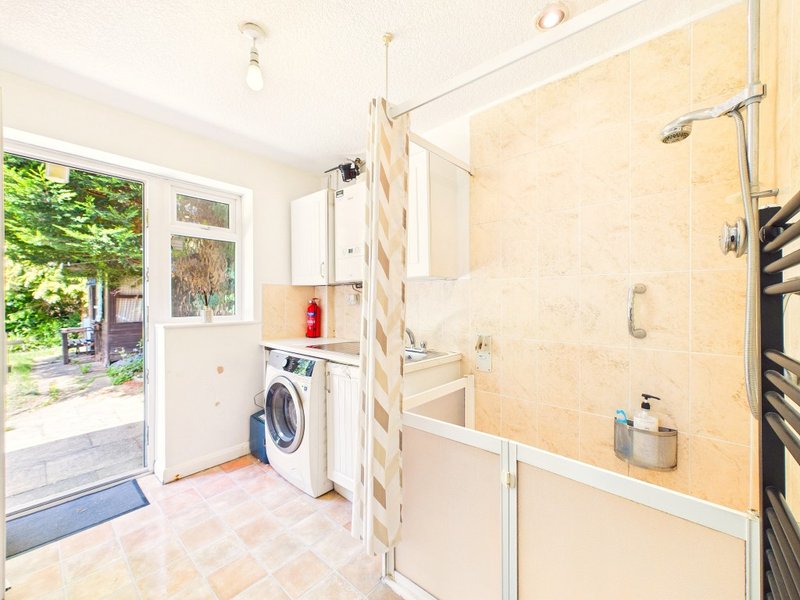 Bright bathroom with shower cubicle, washing machine, and access to garden through door