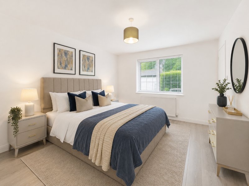 Modern bedroom with double bed, neutral bedding, wooden nightstands, framed wall art, and round mirror