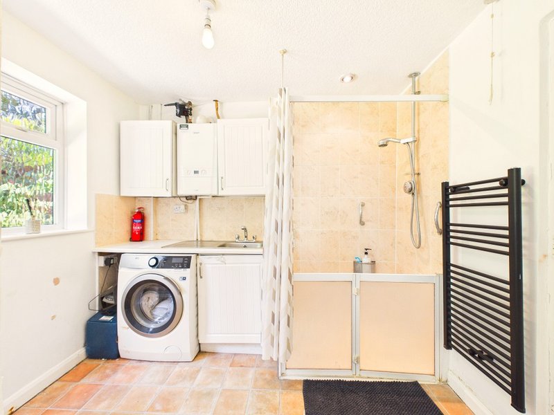 Modern bathroom with washing machine, shower enclosure, heated towel rail and beige tile